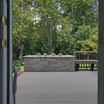 A completed TimberTech deck with a stone planter made from Techo-Bloc Semma wall block. The vie from inside showcases the planter.